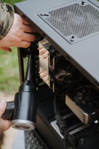 Dépoussiérage PC Close-up of hands cleaning the interior of a PC case with a duster, focusing on computer care and maintenance.